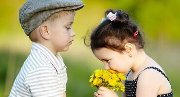 Malé dievča a chlapec voňajú kvety.
