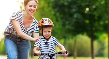 mother teaches child son to ride a bike in the Park in nature