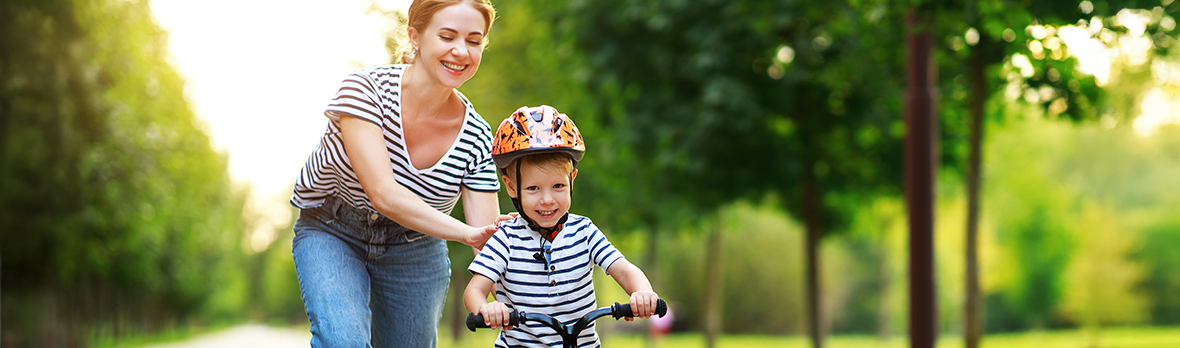 mother teaches child son to ride a bike in the Park in nature