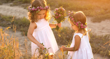 Girls on a country road with wreaths of flowers on their heads collecting herbarium