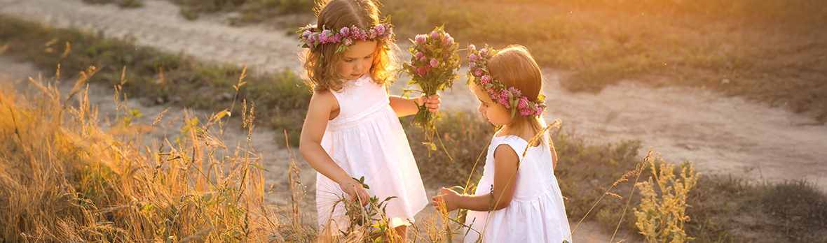 Girls on a country road with wreaths of flowers on their heads collecting herbarium